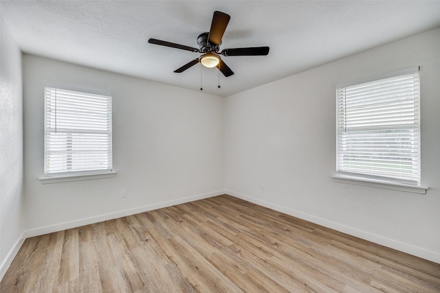 unfurnished room with a textured ceiling, light wood-type flooring, and ceiling fan