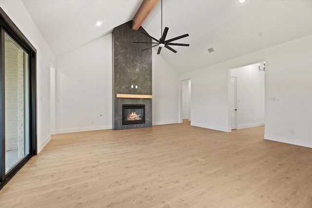 unfurnished living room featuring light wood-type flooring, a wealth of natural light, lofted ceiling with beams, and a tile fireplace