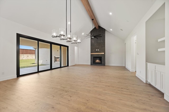 unfurnished living room featuring ceiling fan with notable chandelier, a large fireplace, beam ceiling, high vaulted ceiling, and light hardwood / wood-style floors