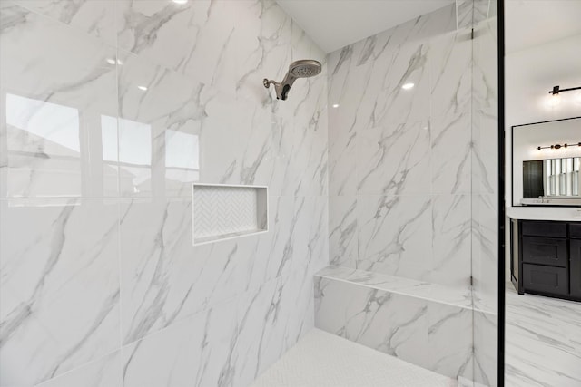 bathroom with tiled shower and vanity