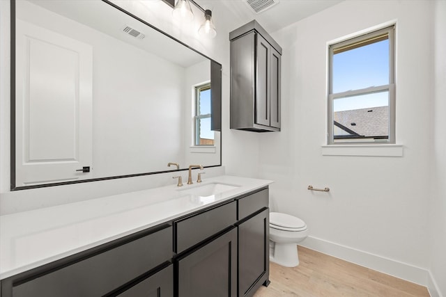 bathroom with hardwood / wood-style floors, vanity, a healthy amount of sunlight, and toilet