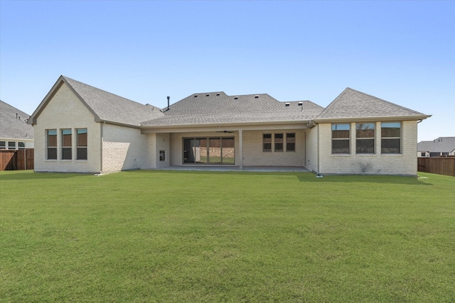 rear view of property with ceiling fan and a yard