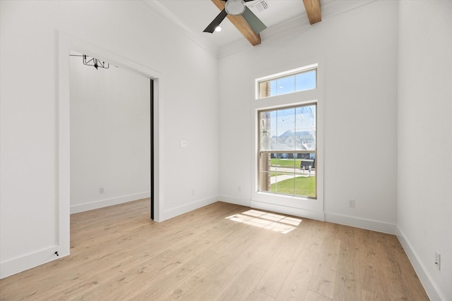 empty room featuring beamed ceiling, light hardwood / wood-style floors, and ceiling fan