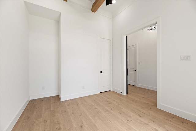 empty room with beamed ceiling and light hardwood / wood-style floors