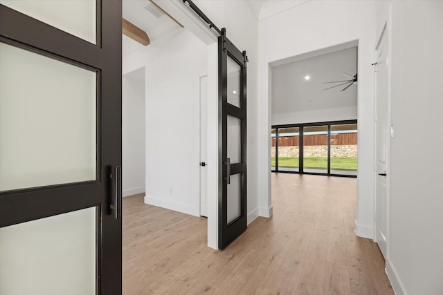 hall featuring a barn door, beam ceiling, and light hardwood / wood-style flooring