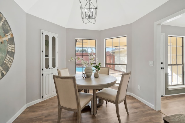 dining area with dark hardwood / wood-style flooring, an inviting chandelier, and lofted ceiling