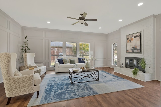 living room with dark hardwood / wood-style flooring, a brick fireplace, and ceiling fan