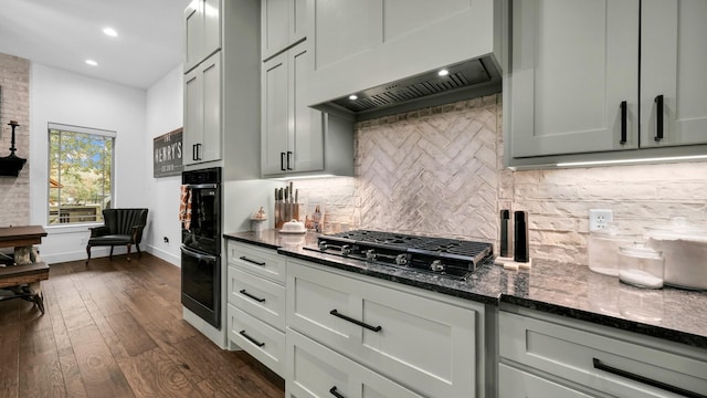 kitchen with gas cooktop, dark hardwood / wood-style flooring, backsplash, dark stone counters, and custom range hood