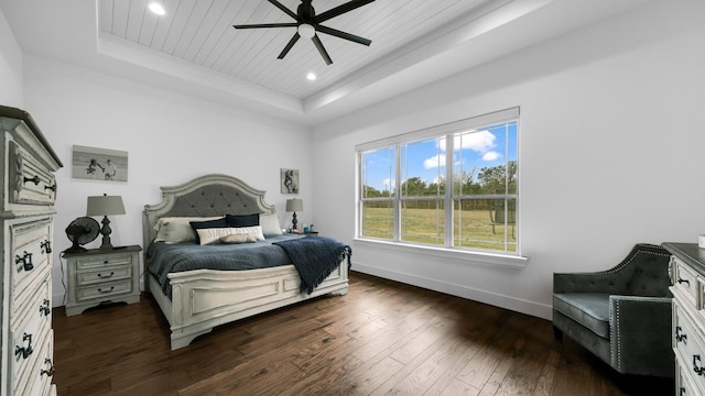 bedroom featuring ceiling fan, dark hardwood / wood-style floors, wood ceiling, and a tray ceiling