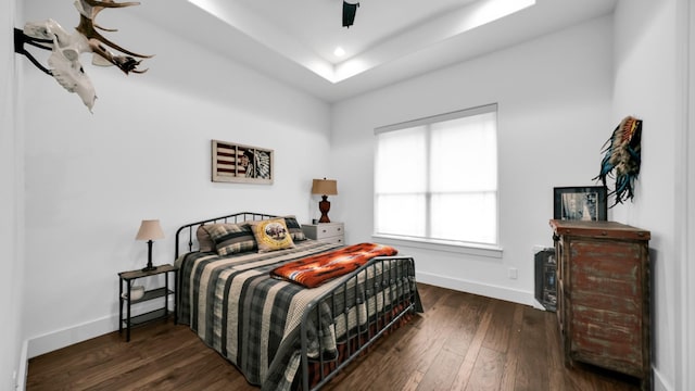 bedroom featuring a raised ceiling, ceiling fan, and dark hardwood / wood-style flooring