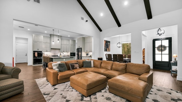 living room featuring high vaulted ceiling, an inviting chandelier, sink, beamed ceiling, and wood-type flooring