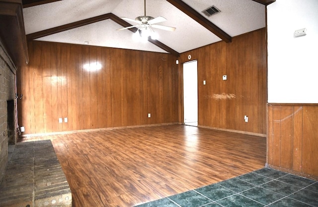 unfurnished living room with vaulted ceiling with beams, dark hardwood / wood-style flooring, a textured ceiling, and wooden walls