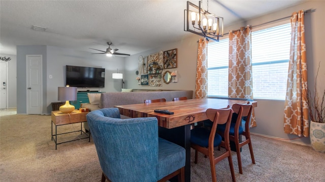 carpeted dining room featuring ceiling fan with notable chandelier and a textured ceiling