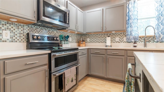 kitchen featuring stainless steel appliances, gray cabinetry, tasteful backsplash, and sink