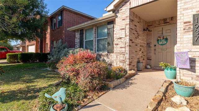 view of exterior entry featuring a lawn