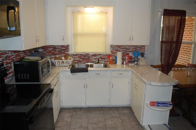 kitchen with black range with electric stovetop, sink, and white cabinets