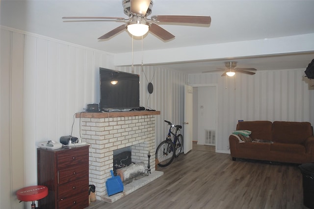 living room featuring ceiling fan, wood-type flooring, and a fireplace