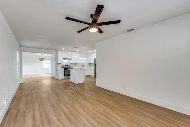 unfurnished living room featuring ceiling fan, light hardwood / wood-style floors, and sink