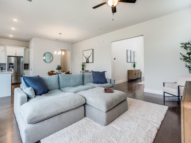 living room with ceiling fan with notable chandelier and dark hardwood / wood-style floors