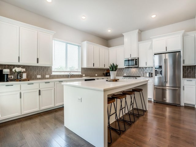 kitchen featuring white cabinets, a center island, stainless steel appliances, and dark wood-type flooring