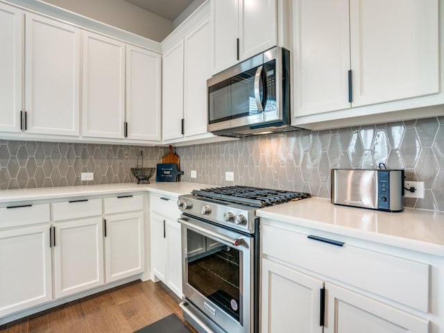 kitchen featuring decorative backsplash, white cabinetry, light hardwood / wood-style floors, and appliances with stainless steel finishes