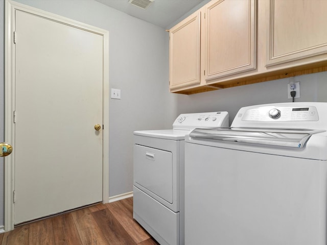 laundry area with washing machine and dryer, cabinets, and dark wood-type flooring