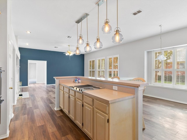 kitchen featuring a center island, hanging light fixtures, dark hardwood / wood-style floors, and stainless steel gas cooktop