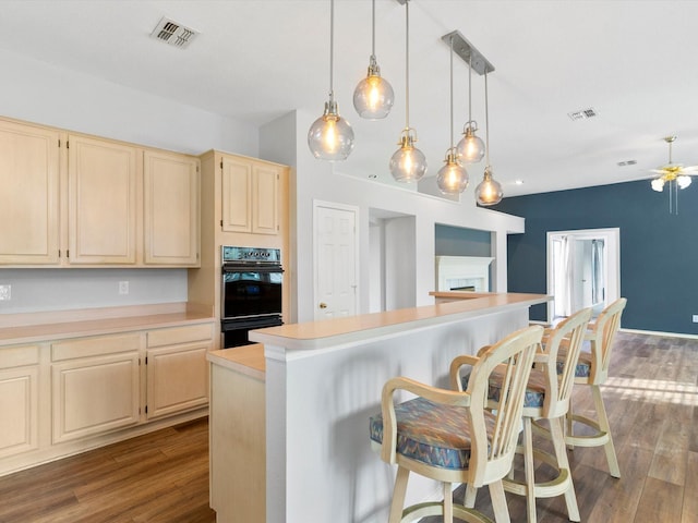 kitchen featuring a kitchen breakfast bar, decorative light fixtures, a kitchen island, and dark wood-type flooring