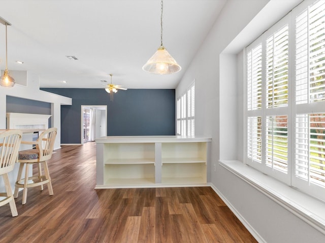 kitchen with ceiling fan, dark wood-type flooring, and decorative light fixtures