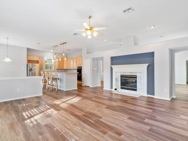 unfurnished living room with ceiling fan, light wood-type flooring, and a fireplace