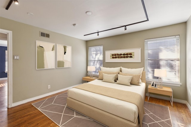 bedroom with wood-type flooring and rail lighting