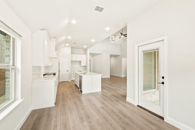 kitchen featuring sink, white cabinets, and a center island with sink