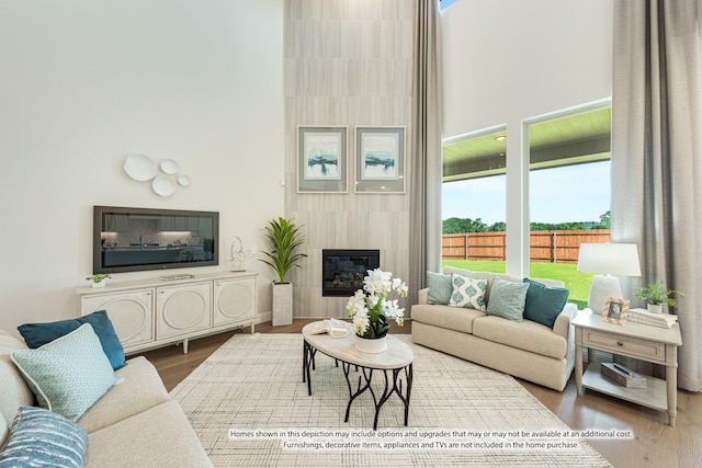 living room with a fireplace, wood-type flooring, and a high ceiling