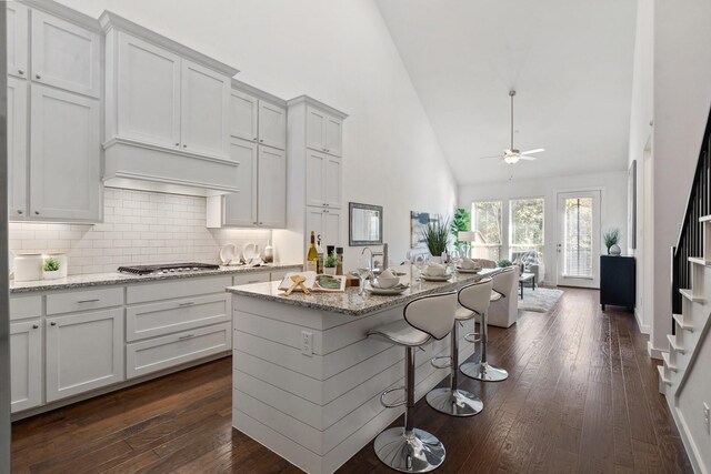 kitchen featuring dark hardwood / wood-style floors, white cabinetry, light stone countertops, and high vaulted ceiling