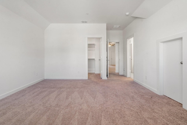 unfurnished bedroom with light carpet, a spacious closet, and a closet