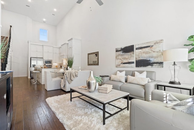 living room featuring dark hardwood / wood-style floors, ceiling fan, and a high ceiling