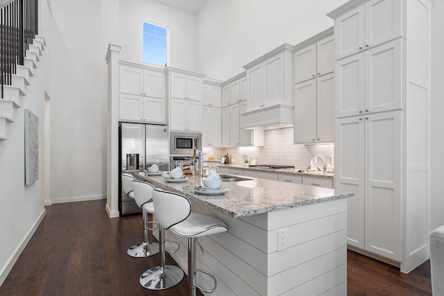 kitchen with white cabinetry, a center island with sink, sink, and appliances with stainless steel finishes