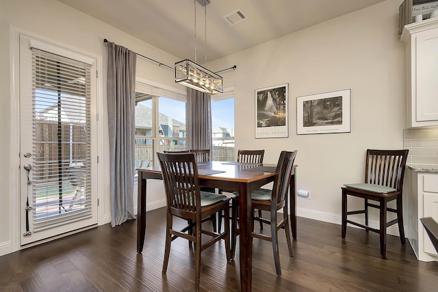 dining space with dark wood-type flooring and a chandelier