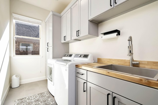 laundry room with washer and dryer, light tile patterned floors, cabinets, and sink