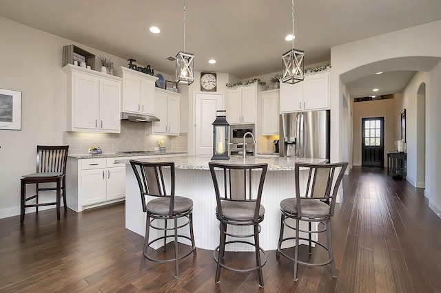 kitchen featuring light stone counters, dark hardwood / wood-style floors, a kitchen island with sink, white cabinets, and appliances with stainless steel finishes