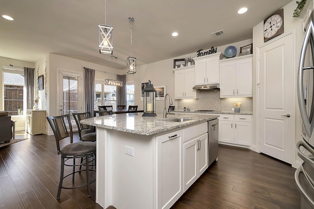 kitchen with white cabinets, dark hardwood / wood-style floors, sink, and an island with sink