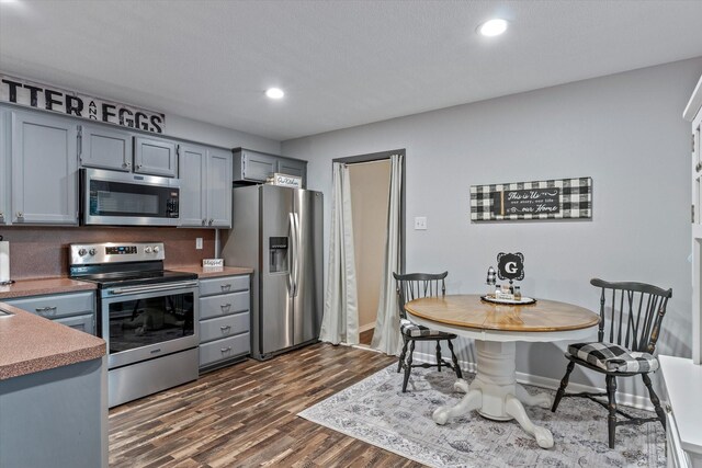 kitchen with stainless steel appliances, dark hardwood / wood-style floors, and gray cabinetry