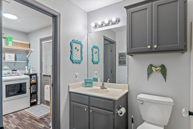 bathroom featuring vanity, a textured ceiling, hardwood / wood-style flooring, washer / dryer, and toilet