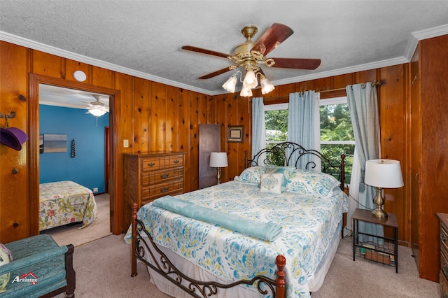 carpeted bedroom with crown molding, ceiling fan, a textured ceiling, and wood walls