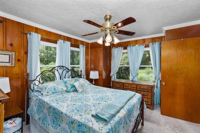 carpeted bedroom with crown molding, a textured ceiling, and wood walls