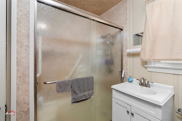 bathroom featuring a shower with door and vanity