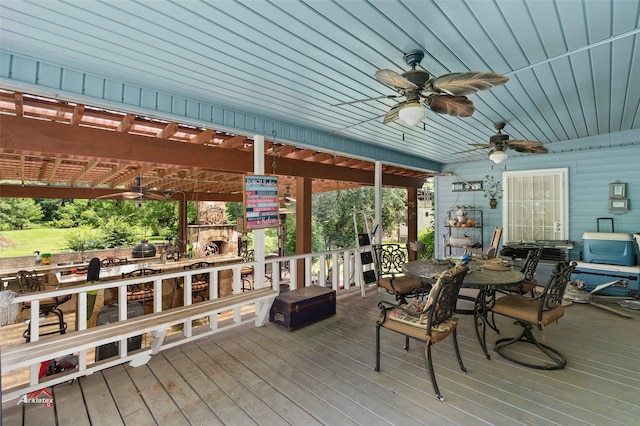 deck with ceiling fan and an outdoor stone fireplace