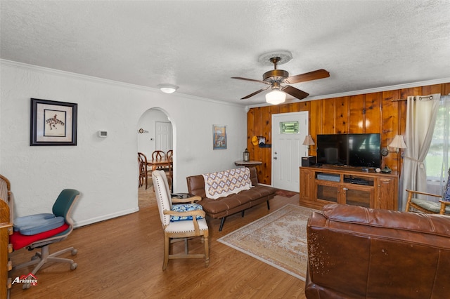 living room with ceiling fan, hardwood / wood-style flooring, ornamental molding, and a textured ceiling