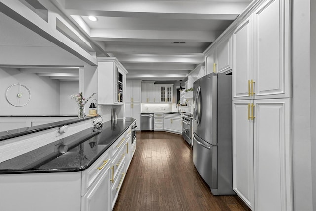 kitchen featuring sink, dark wood-type flooring, dark stone countertops, white cabinets, and appliances with stainless steel finishes