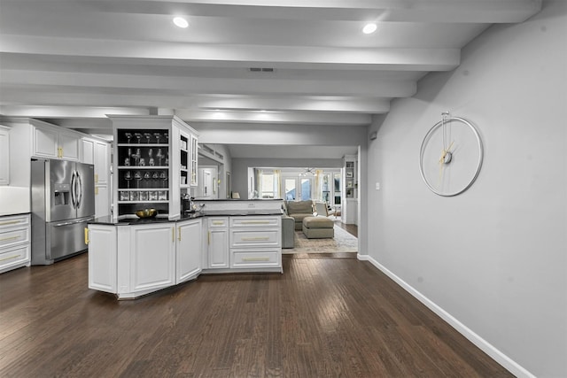 kitchen featuring stainless steel fridge, white cabinetry, dark hardwood / wood-style floors, kitchen peninsula, and beamed ceiling